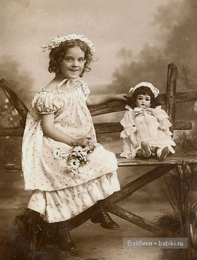 Девочка в чепце, кукла рядом, сидят