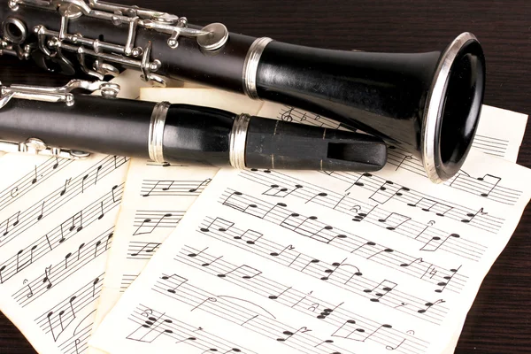 Музыкальные ноты и кларнет на деревянный стол — стоковое фото