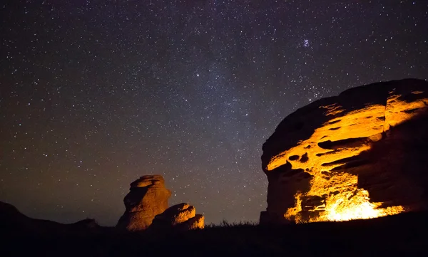 Огни bounfire большая скала с сидящим человеком Стоковое Фото